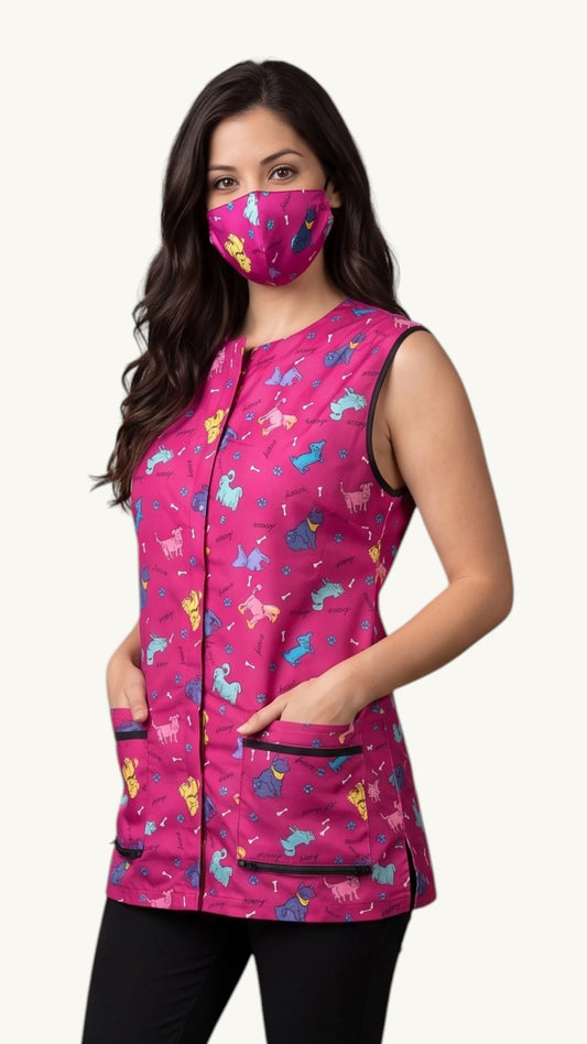 Three-quarter length view of a woman with long dark wavy hair modeling the Ladybird Line 22 pink dog design pet grooming face mask, paired with a matching sleeveless grooming vest and black pants against a solid light background.