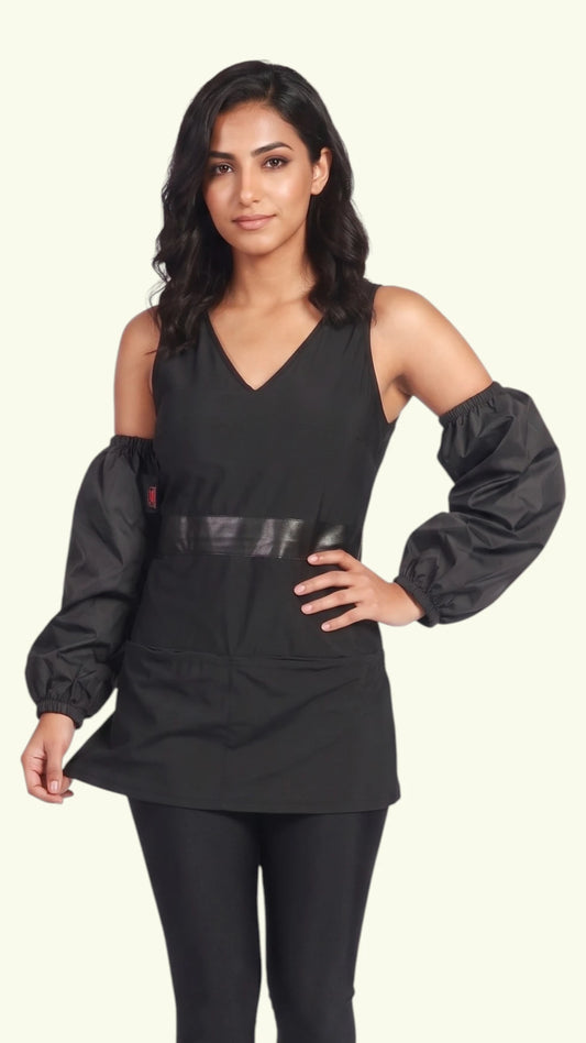 Front view of a dark-haired woman modeling the Ladybird Line 606 waterproof black dog bathing arm sleeves with elastic cuffs, worn with a sleeveless black top and pants against an off-white background.