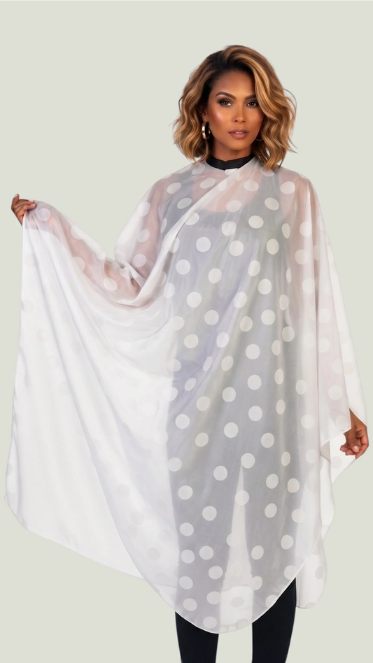 Front view of a woman with highlighted wavy bob hair modeling the Ladybird Line 3600 white polka dot water repellent bride styling cape, holding out one side over black attire against a solid light studio background.