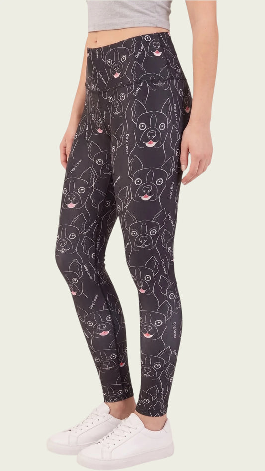 Side profile view of a woman modeling the Ladybird Line 124 Dog Lover Shadow Hair & Bleach Resistant Grooming Leggings featuring a black dog face line-art print, worn with white sneakers against a beige background.