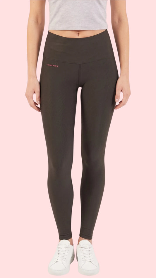 Front view of a woman modeling the Ladybird Line 125 Black Shadow Hair & Bleach Resistant Grooming Leggings, paired with a gray cropped tank top and white sneakers against a pale pink background.