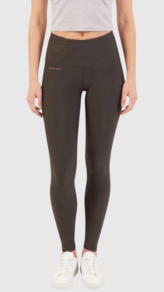 Front full-body view of a model wearing high-waisted black Ladybird Line 125 Black Shadow Grooming Leggings with a small silver logo on the left hip, paired with a light grey short-sleeve crop top and white sneakers, set against a light grey background.
