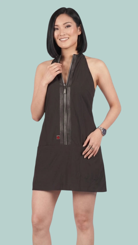 Front view of an Asian woman modeling the Ladybird Line 150 Rhinestone Zipper Pro Water Resistant Salon Grooming Apron in black, featuring a rhinestone zipper accent with faux leather trim against a solid light blue background.
