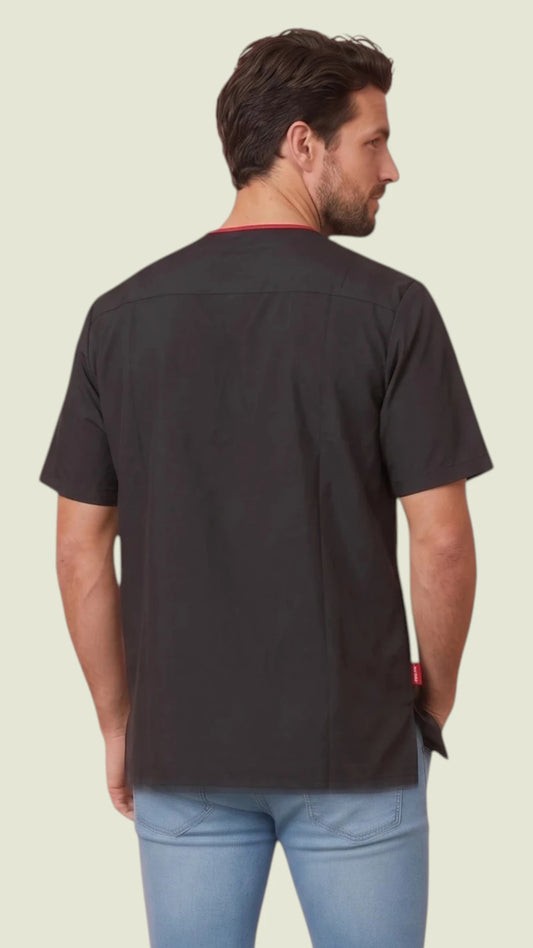 Back view of a man with short brown hair and a beard modeling the Ladybird Line 415 Men's Waterproof & Bleach Resistant Short Sleeve Scrub Top, showing the solid black back panel and red inner collar accent, worn over light blue jeans against a light beige background.