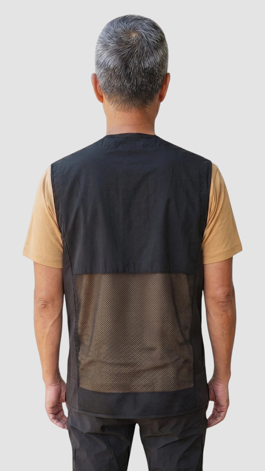 Back view of an Asian man with short grey hair modeling the Ladybird Line 880 Black V-Neck Waterproof & Bleach Resistant Mesh Back Vest, showing the breathable lower mesh back panel, worn over a gold t-shirt and dark pants against a light grey background.