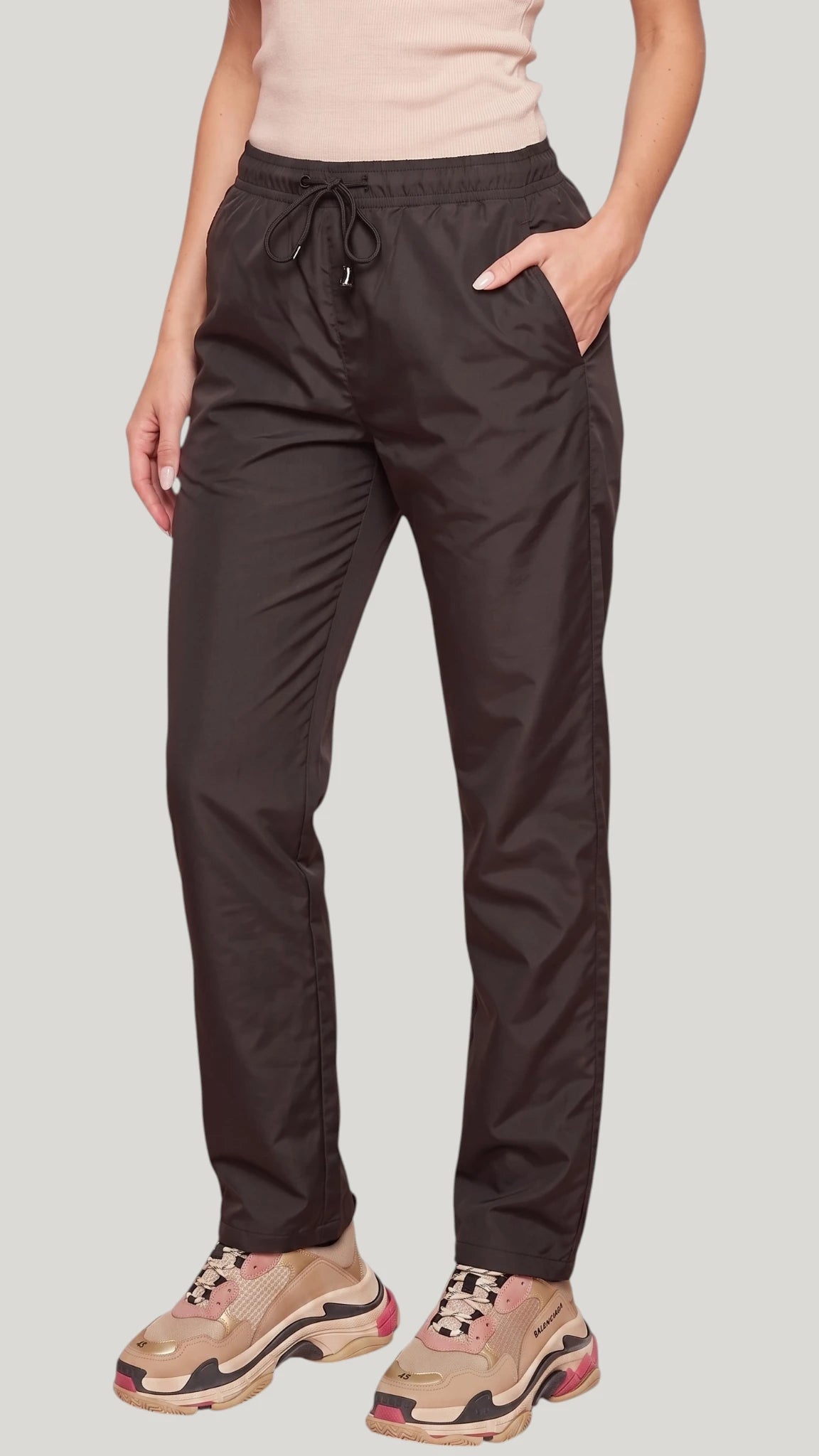 Front view of a woman with hand in pocket modeling the Ladybird Line 925 Unisex Black Water Resistant & Bleach Resistant Grooming Pants, paired with a light pink sleeveless top and beige sneakers against a light grey background.