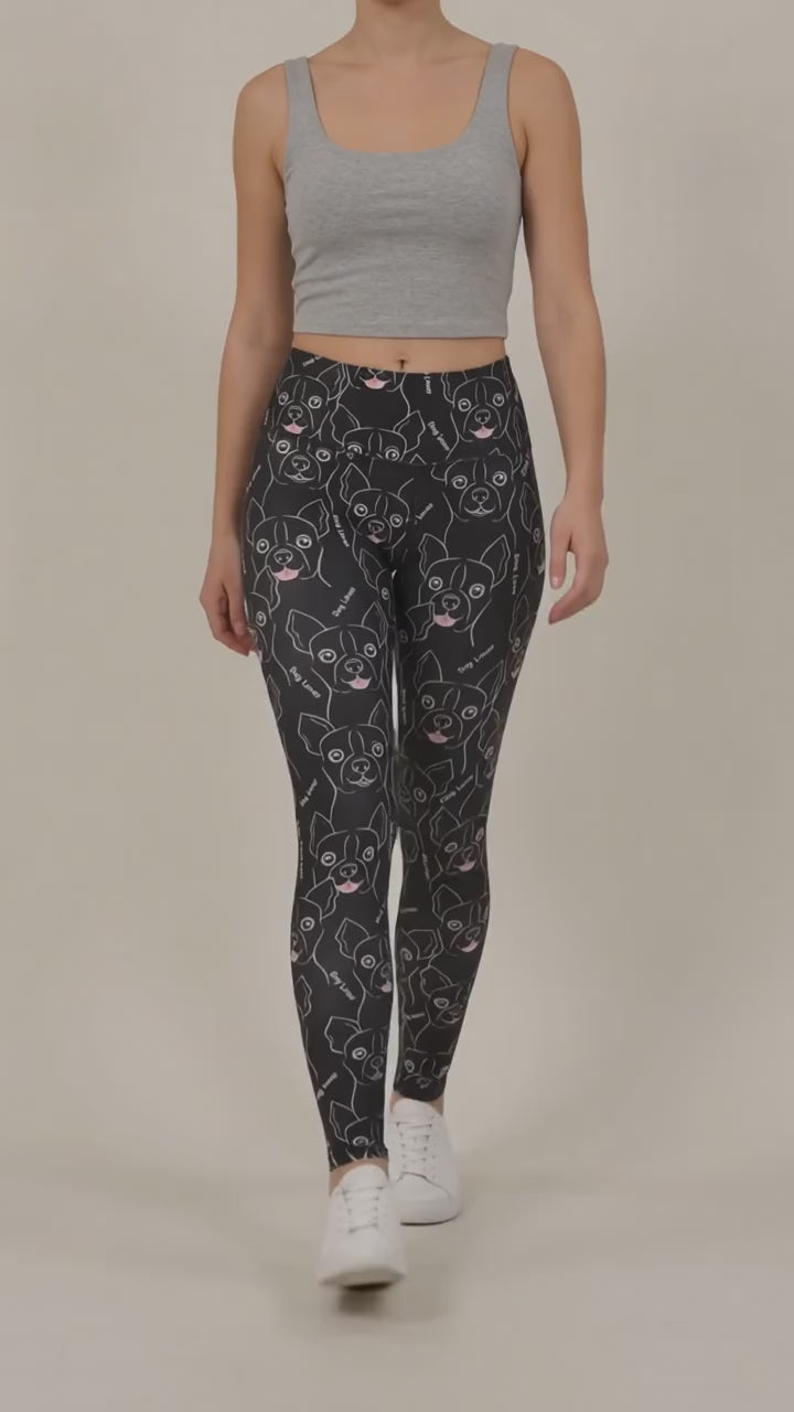 Back view of a woman modeling the Ladybird Line 124 Dog Lover Shadow Hair & Bleach Resistant Grooming Leggings featuring a black dog face line-art print, worn with white sneakers against a beige background.